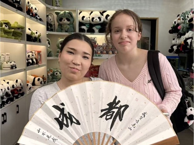 Students holding a calligraphy fan in a panda valley gift shop